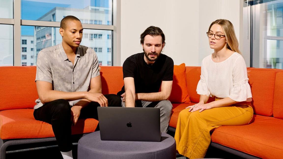 three colleagues on casual seating viewing laptop